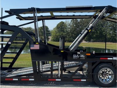 Rows of stacked rectangular and square American-sourced steel tubes and beams stretch into the background of a manufacturing facility, with a person visible in the distance.